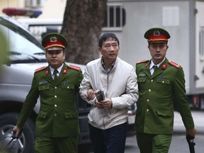 Trinh Xuan Thanh, center, is led into a courtroom by police in Hanoi, Vietnam, Wednesday, Jan. 24, 2018. Thanh, former chairman of state energy giant PetroVietnam's construction arm, is accused of embezzling $622,000 from a property project. Thanh was sentenced to life in prison on Monday for embezzlement in thermo power plant. Germany in August accused Vietnamese agents of snatching Thanh from a Berlin park, a charge Vietnam denied. The incident strained relations between the two countries.