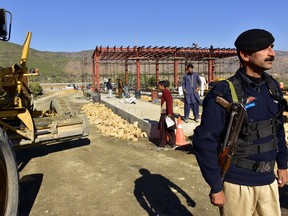 In this Dec. 22, 2017, photo, a Pakistani police officer stands guard at the site of Pakistan China Silk Road in Haripur, Pakistan. From Pakistan to Tanzania to Hungary, projects under Chinese President Xi Jinping's signature "Belt and Road Initiative" are being canceled, renegotiated or delayed due to disputes about costs or complaints host countries get too little out of projects built by Chinese companies and financed by loans from Beijing that must be repaid.