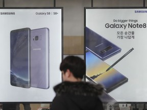 In this Monday, Jan. 8, 2018, photo, a man walks by advertisements of Samsung Electronics' smartphone at its shop in Seoul, South Korea. Samsung Electronics said Tuesday its October-December operating profit jumped 64 percent to a record high.