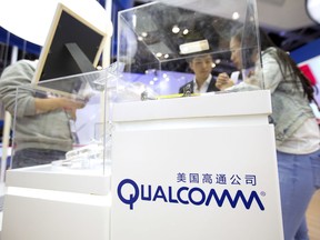 FILE - In this Thursday, April 27, 2017 file photo, visitors look at a display booth for Qualcomm at the Global Mobile Internet Conference (GMIC) in Beijing. The European Union is slapping a $1.23 billion fine on U.S. chipmaker Qualcomm for abusing its market dominance in the lucrative sector of vital components in smartphones and tablets.