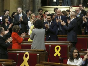 Deputy Roger Torrent, center, is congratulated after being elected as the new president of the Catalan parliament after a parliamentary session where elected lawmakers meet for the first time after regional elections in Catalonia, Barcelona, Spain, Wednesday, Jan. 17, 2018. Catalonia's new parliament has begun meeting amid looming questions about the role that fugitive and jailed politicians will play in the chamber's separatist majority and the future regional government