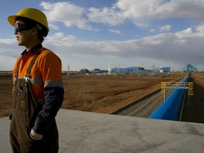 A Mongolian worker looks out from operations along the blue conveyor belt that moves rock from the crusher to the concentrator area at the Oyu Tolgoi mine October 11, 2012 in the south Gobi desert, Khanbogd region, Mongolia.