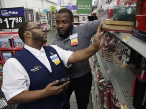 In this Thursday, Nov. 9, 2017, photo, Walmart employee Kenneth White, left, is coached by Shabazz Bonner while using an inventory app during a class at the Walmart Academy at the store in North Bergen, N.J. The retail industry is being radically reshaped by technology and nobody feels that disruption more starkly than the 16 million Americans working as shelf stockers, salespeople and cashiers.