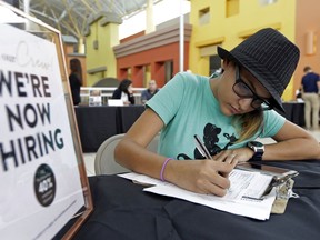 FILE - In this Oct. 4, 2017 file photo, job seeker Alejandra Bastidas fills out an application at a job fair in Sweetwater, Fla.  U.S. workers' wages and benefits grew 2.6 percent last year, the fastest 12-month pace since the spring of 2015. The 12-month gain in wages and benefits came despite a slight slowdown at the end of last year with wages and benefits rising 0.6 percent in the fourth quarter, a tiny dip from a 0.7 percent gain in the third quarter. Still, the 12-month gain was an improvement from a 2.2 percent gain for the 12 months ending in December 2016.