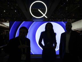 FILE - In this Friday, Jan. 6, 2017, file photo, attendees stand in front of a QLED TV at the Samsung booth during CES International in Las Vegas. TV manufacturers are showcasing new models at the 2018 CES gadget show in Las Vegas, all with acronyms to set their sets apart and get consumers to spend more.