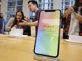 FILE - In this Friday, Nov. 3, 2017, file photo, customers buy the iPhone X at the Apple Store on New York's Fifth Avenue. Apple shares have been falling in early 2018 on fears that the iPhone X has not been a hit with customers.