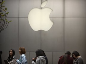 FILE - In this Friday, Oct. 20, 2017, file photo, people stand in line near an Apple Store at an outdoor shopping mall in Beijing, China. On Wednesday, Jan. 17, 2018, Apple announced it is planning to build another corporate campus and hire 20,000 workers during the next five years as part of a $350 billion commitment to the U.S. economy.