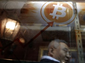 FILE - In this Friday, Dec. 8, 2017, file photo, a man uses a Bitcoin ATM in Hong Kong. On Thursday, Jan. 11, 2018, the value of numerous forms of digital currency tumbled after South Korea, a hotbed for currencies like bitcoin, said it was weighing a trading ban.