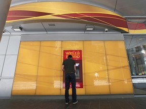 FILE - In this Thursday, April 13, 2017, file photo, a man uses a Wells Fargo ATM in Charlotte, N.C. On Friday, Jan. 12, 2018, Wells Fargo said its fourth-quarter earnings rose 17 percent from a year earlier, as the consumer banking giant benefited from the recently passed GOP tax bill, but incurred additional costs related to improper sales practices and other matters.