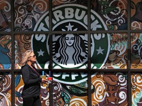 FILE - In this Tuesday, March 21, 2017, file photo, a woman walks past a Starbucks coffee shop in Sewickley, Pa. Starbucks Corp. reports earnings Thursday, Jan. 25, 2018.