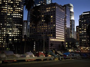 FILE - In this Dec. 1, 2017 file photo, homeless tents are dwarfed by skyscrapers as 63-year-old Vincent, who only gave his first name, sorts his belongings in Los Angeles. President Donald Trump's administration is announcing $2 billion in grants for local programs to deal with homelessness. The funding total is a record for the Continuum of Care grants, but only a small increase over recent years. The announcement comes as the administration is calling for cuts to housing programs and as the West Coast is dealing with a homeless crisis.