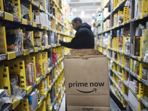 FILE - In this Dec. 20, 2017, file photo, a clerk reaches to a shelf to pick an item for a customer order at the Amazon Prime warehouse, in New York. Amazon says it is boosting the price of its monthly Prime membership fees for new and existing members by nearly 20 percent. The online retailer says its annual membership fee of $99 will not change.