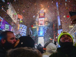 People celebrate New Year as confetti fall down after the countdown to midnight in Times Square during New Year's celebrations, Monday, Jan. 1, 2018, in New York.