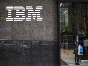 In this Wednesday, April 26, 2017, photo, a woman looks out from the lobby next to the logo displayed on the IBM Building in New York. On Thursday, Jan. 18, 2018, IBM Corp. reports financial results.