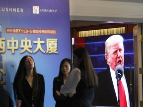 FILE- In this May 7, 2017 file photo, a projector screen shows a footage of U.S. President Donald Trump as workers wait for investors at a reception desk during an event promoting EB-5 investment in a Kushner Companies development, at a hotel in Shanghai, China. The family real estate company once run by Jared Kushner is no longer seeking $150 million from wealthy Chinese for a two-tower residential complex in Jersey City, N.J., after government ethics experts in 2017 blasted the Kushner Cos. for what they said was an attempt to use its ties to the White House to raise the money. (AP Photo, File)