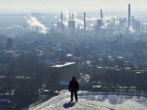 FILE - In this Jan. 19, 2016 file photo, a man watches a BP refinery in Gelsenkirchen, Germany. New York City officials say they will begin the process of dumping about $5 billion in pension fund investments in fossil fuel companies, including BP, because of environmental concerns.
