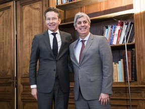 Outgoing leader Jeroen Dijsselbloem, left, of the Netherlands smiles after handing over power of the so-called eurogroup to Portugal's Mario Centeno, right, in Paris, Friday, Jan.12, 2018. The euro zone's new leader says he hopes to use his term to bring the 19 countries that use the currency closer together and toughen their ability to weather future crises. (AP Photo)