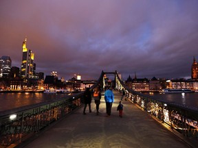 People walk over the "Eiserne Steg" bridge in Frankfurt, Germany, Sunday evening, Jan. 28, 2018.