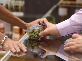 A budtender (right) shows cannabis buds to a customer at the Green Pearl Organics dispensary in Desert Hot Springs on the first day of legal recreational marijuana sales in California.