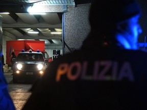 Police officers stand next to trucks parked in a garage during an operation aiming to break up a Chinese transport mafia, in Prato, Italy, Jan. 18, 2018. Anti-mafia prosecutors in Italy say they have broken up a Chinese organized crime ring that used money from criminal activities to force their way into the transport sector, not only in Italy but elsewhere in Europe.