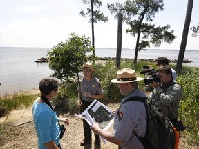 FILE This Thursday June 5, 2014 file photo shows former US Secretary of the Interior, Sally Jewell, left, as she listens to park service rangers during a tour of Jamestown Island in Jamestown, Va. A power company is getting set to build 17 transmission towers in Virginia near colonial Jamestown Island. And already the utility has begun paying out $90 million for projects to blunt the impact on significant historic areas.