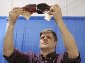 In this Monday, Jan. 29, 2018 photo, Mark Isselhardt, a University of Vermont extension maple specialist, studies the color of maple syrup entries in an annual contest at the Vermont Farm Show in Essex Junction, Vt. Vermont is the country's largest producer of maple syrup.