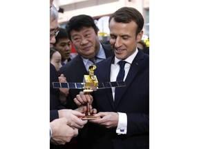 French President Emmanuel Macron receives a scale model of the CFOSAT (China-France Oceanography SATellite) during his visit to the China Academy of Space Technology in Beijing, China, Wednesday, Jan. 10, 2018.