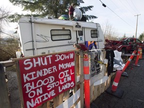 A protester who goes by the name Uni stands on top of a trailer outside the main gates of Kinder Morgan in Burnaby, B.C., Wednesday, Jan. 10, 2018.