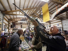 In this Oct. 20, 2017 photo, customer Andy Muscato looks over a rifle before an auction at Johnny's Auction House, where the company handles gun sales for several police departments and the Lewis County Sheriff's Office, in Rochester, Wash. Law enforcement officials around the U.S. are split over the longtime practice among police departments of selling the guns they confiscate.