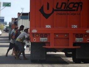 In this Jan. 23, 2018 photo, men try to steal rice from a cargo truck arriving to the port in Puerto Cabello, Venezuela. Sporadic looting, food riots and protests driven by hunger have surged in Venezuela, a country that's no stranger to unrest.
