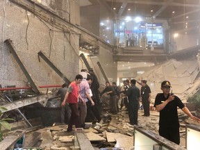 Indonesian security stand near the ruin of a structure inside the Jakarta Stock Exchange tower in Jakarta, Indonesia, Monday, Jan. 15, 2018. A structure inside the Jakarta Stock Exchange tower collapsed Monday, injuring at least several people and forcing a chaotic evacuation. (AP Photo)
