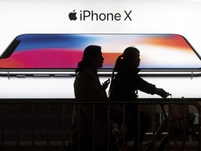 People pass an advertisement for the iPhone X in Beijing, China.