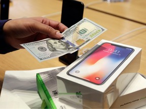 A customer hands over cash as she pays for an iPhone X at the Apple Store on New York's Fifth Avenue.