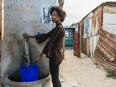 A resident fills a plastic container with water from the communal tap in the Khayelitsha township, Cape Town, South Africa, on Friday, Feb. 9, 2018.