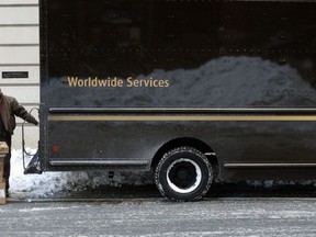 In this Friday, Jan. 5, 2018, photo, a UPS delivery driver loads his cart with packages from his truck, in Boston. UPS Inc. reports earnings Thursday, Feb. 1, 2018.
