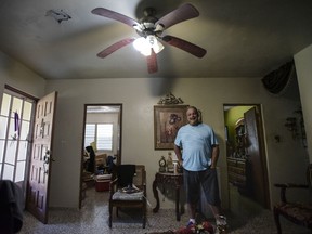 In this Jan. 31, 2018 photo, Jose Luis Rodriguez smiles inside his living room after municipal workers restored power to his home, four months after Hurricane Maria hit Coamo, Puerto Rico. The people of this town have started restoring power on their own, pulling power lines from undergrowth and digging holes for wooden posts in a do-it-yourself effort to solve a small part of the United States' longest-running power outage.