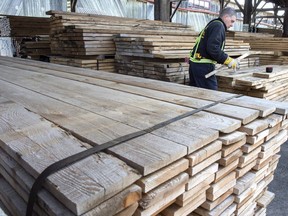 A worker tidies up the wood pile at a lumber yard Tuesday, April 25, 2017 in Montreal. Canadian lumber producers are optimistic for 2018 as strong demand from rising U.S. housing starts and tight supply is expected to keep prices high and more than offset the cost of softwood lumber duties.