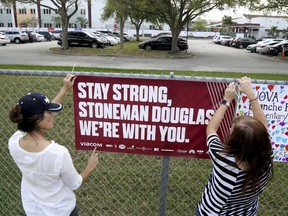 Volunteers hang banners around the perimeter of Marjory Stoneman High School in Parkland, Fla., to welcome back students who will be returning to school Wednesday two weeks after the mass shooting that killed 17 students and staff.
