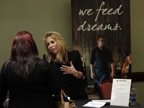 In this Tuesday, Jan. 30, 2018, photo, Grace Ochoa, of Performance Food Service, right, talks with a job applicant at a JobNewsUSA job fair in Miami Lakes, Fla. On Friday, Feb. 2, the U.S. government issues the January jobs report.