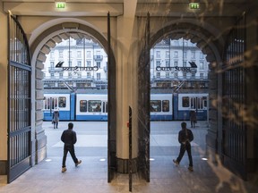 People walk in the front of the Credit Suisse bank at the tram stop Paradeplatz in the square's centre in Zurich, Switzerland, Wednesday, Feb. 14, 2018.