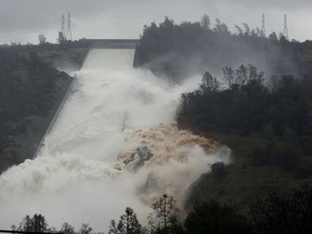 FILE - In this Feb. 9, 2017 file photo, water flows through a break in the wall of the Oroville Dam spillway in Oroville, Calif. One year after the closest thing to disaster at a major U.S. dam in a generation, federal dam regulators say they are looking hard at how they overlooked the built-in weaknesses of old dams like California's Oroville Dam for decades, and expect dam managers around the country to study their old dams and organizations equally hard.