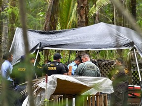 Sheriffs from the Hawaii Department of Public Safety collect details at Coco Palms hotel in a raid in in Wailua on the island of Kauai in Hawaii, Thursday, Feb. 22, 2018. State sheriffs on Thursday removed protesters from the ruins of the Hawaii hotel where they have been squatting since last year in an attempt to block redevelopment of land where Hawaiian chiefs once lived and where Elvis Presley's character got married in the movie "Blue Hawaii."