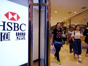 People walk past a HSBC local branch in Hong Kong Tuesday, Feb. 20, 2018. HSBC says its annual pretax profits by 11 percent on strong earnings from Asia, in the latest sign that the London-based global bank's restructuring to focus even more on the region reaps further dividends.