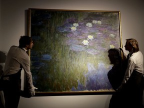 Christie's London auction house staff pose for photographs with Claude Monet's 'Nympheas en fleur', which will feature in the upcoming May 7-11 New York sale of the collection of Peggy and David Rockefeller, at their premises in London, Tuesday, Feb. 20, 2018. The Monet is estimated to fetch $50 million-$70 million (35.7 million to 50 million pounds, 40.5million to 56.7 million euro). The art collection amassed by billionaire David Rockefeller could raise more than $500 million for charity when it is auctioned this spring.
