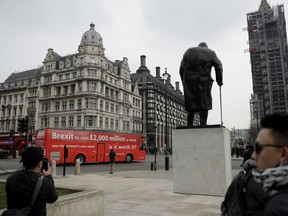 A bus bearing the words "Brexit to cost £2,000 million a week" drives past a statue of Britain's World War II leader Sir Winston Churchill and the scaffolding covered Elizabeth Tower, which contains the bell known as "Big Ben", of the Houses of Parliament at the start a national campaign tour in central London, Wednesday, Feb. 21, 2018. The anti-Brexit bus on Wednesday started an eight day tour, intending to make 33 stops in towns and cities across Britain, with speaker events featuring local business leaders, trade unionists, and politicians.