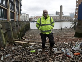 Volunteer Michael Byrne poses for photographs beside plastic bottles washed up on the foreshore at the site of the ancient and no-longer used Queenhithe dock, a designated scheduled monument which dates back to at least the time of King Alfred the Great who lived from 849 to 899 AD, on the north bank of the River Thames in London, Friday, Feb. 9, 2018. Amid growing evidence of dire amounts of waste in the world's oceans, conservation is becoming a selling point for firms trying to jump on the bandwagon of concern about the flood of plastic choking sea life.
