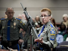 FILE - In this Jan. 28, 2013, file photo, firearms training unit Detective Barbara J. Mattson, of the Connecticut State Police, holds up a Bushmaster AR-15 rifle, the same make and model of gun used by Adam Lanza in the Sandy Hook School shooting, during a hearing of a legislative subcommittee in Hartford, Conn. Remington, the gunmaker beset by falling sales and lawsuits tied to the Sandy Hook Elementary School massacre, said Monday, Feb. 12, 2018, that it has reached a financing deal that would allow it to continue operating as it files for Chapter 11 bankruptcy protection.