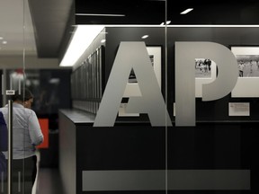 FILE- In this April 18, 2017, file photo, people walk by Associated Press photographs on display at the AP headquarters in New York. The AP is expanding its collaboration with the Howard Hughes Medical Institute's Department of Science Education, a move that will bolster its health and science coverage over the next three years. The AP started working with HHMI last year as a way to enhance the news cooperative's coverage of health and science.