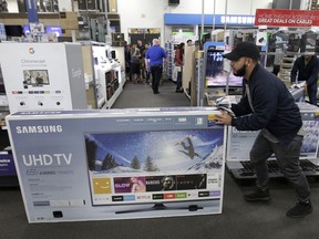FILE - In this Nov. 23, 2017, file photo, Jesus Reyes pushes a television down an aisle as he shops at a Black Friday sale at a Best Buy store in Overland Park, Kan. On Wednesday, Feb. 14, 2018, the Commerce Department releases U.S. retail sales data for January.