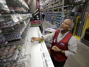 In this Friday, Feb. 23, 2018 photo sales associate Larry Wardford, of Holliston, Mass., places items on selves at a Lowe's retail home improvement and appliance store, in Framingham, Mass. Lowe's Companies Inc. reports financial results on Wednesday, Feb. 28, 2018.